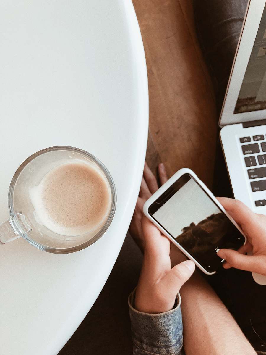 electronics person sitting in-front of white table with clear glass teacup mobile phone